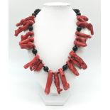 An exotic looking black onyx necklace adorned with large natural red coral pieces from South