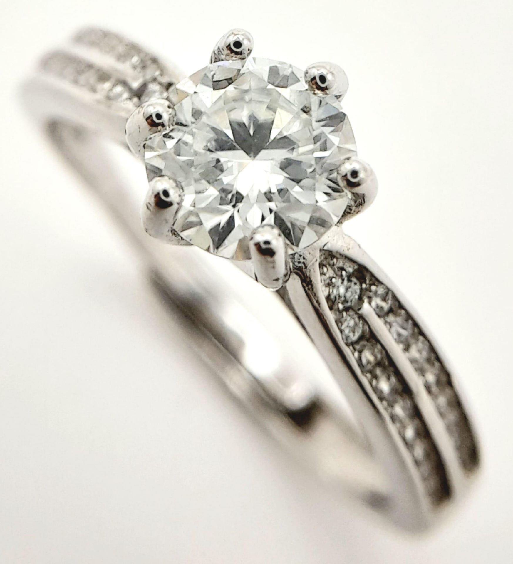 A sterling silver ring with a round cut moissanite (1 carat) and two bands of moissanites on each