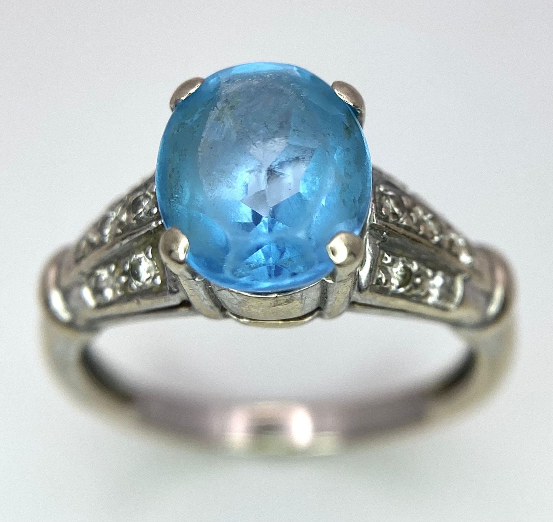 A vintage, 9 K white gold ring with a large, oval cut, vivid blue aquamarine and three bands of