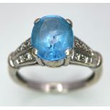 A vintage, 9 K white gold ring with a large, oval cut, vivid blue aquamarine and three bands of