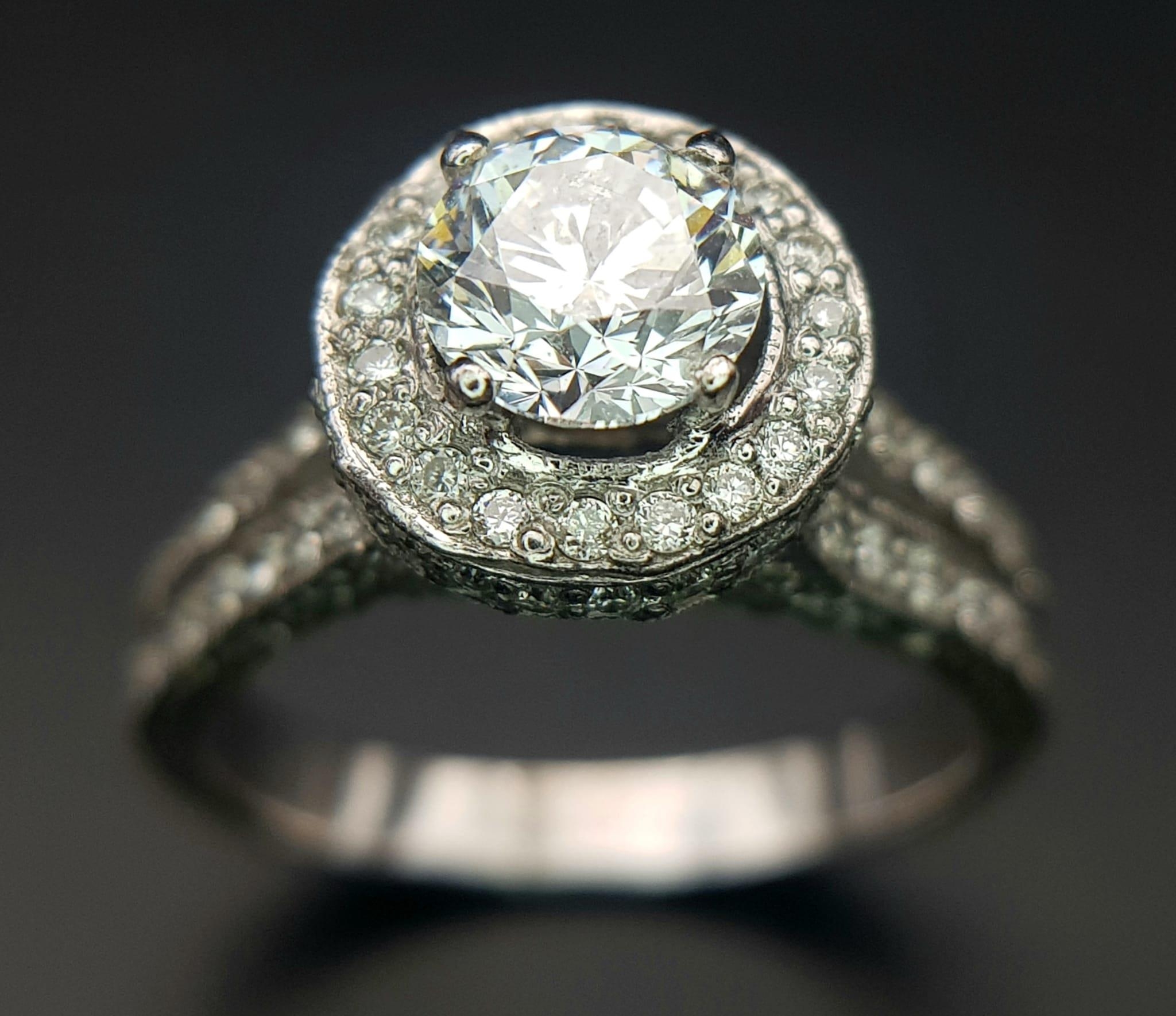 An 18 K white gold ring with a brilliant cut diamond (1.01 carats) surrounded by diamonds on the top