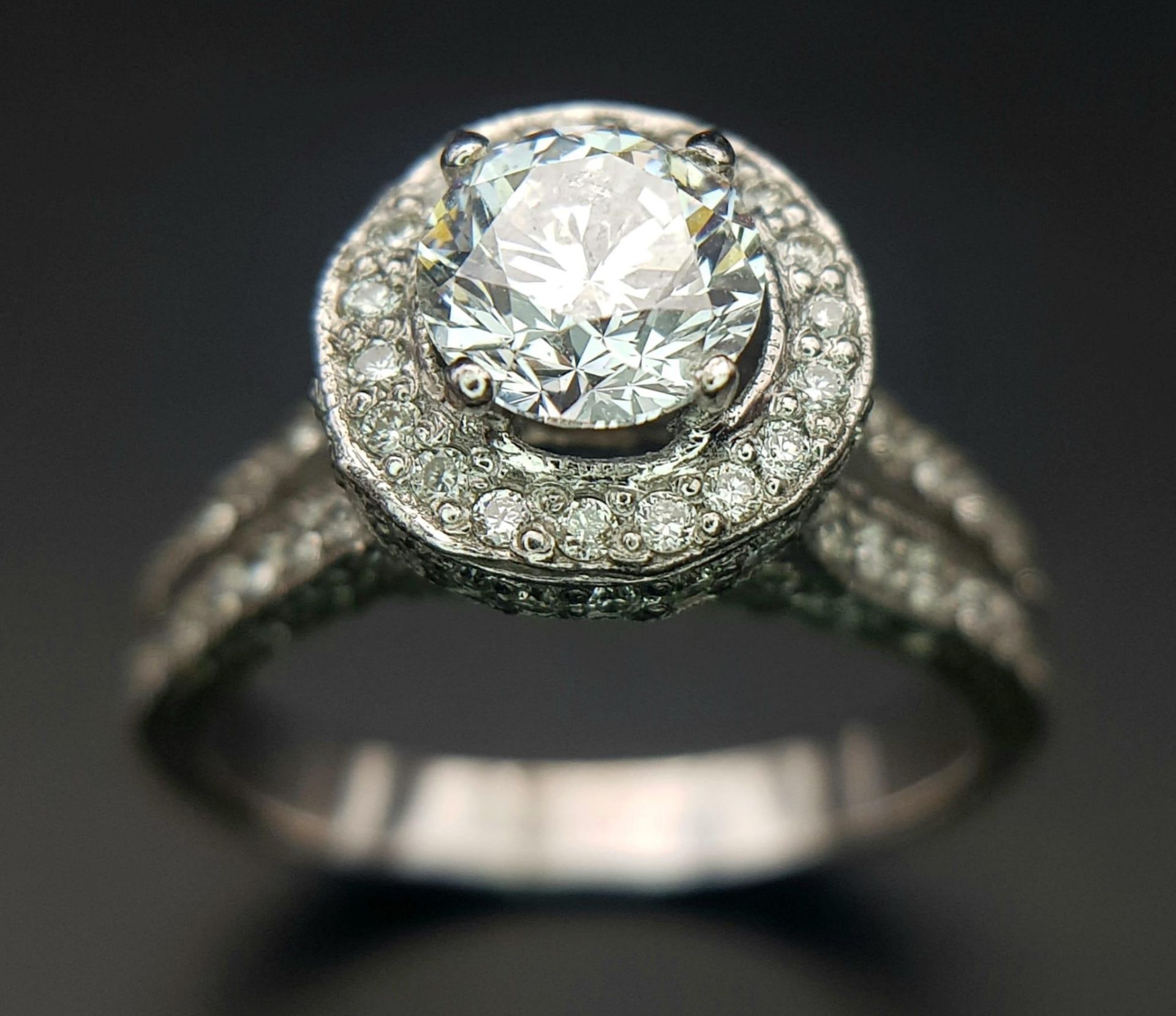 An 18 K white gold ring with a brilliant cut diamond (1.01 carats) surrounded by diamonds on the top