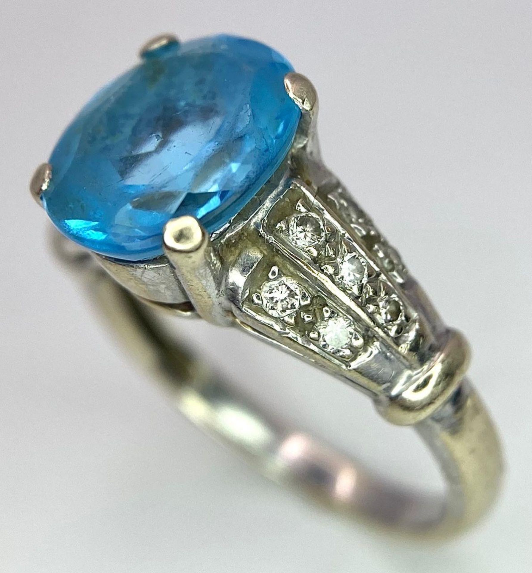 A vintage, 9 K white gold ring with a large, oval cut, vivid blue aquamarine and three bands of - Image 3 of 5