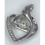 An 18K White Gold and Diamond Heart Pendant. A spinning central round cut diamond powers this