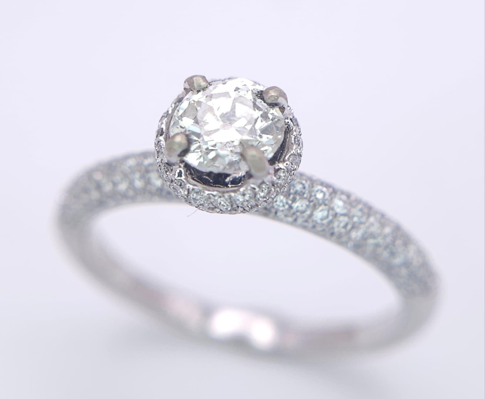 A 14K WHITE GOLD DIAMOND DIAMOND HALO RING WITH FULL SET SHOULDERS AND COLLET. 1.10CT. 2.9G. SIZE - Image 2 of 7