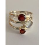 SILVER TREBLE BAND RING. Set with MOONSTONE and GARNETS. Having markings for 925 SILVER and the