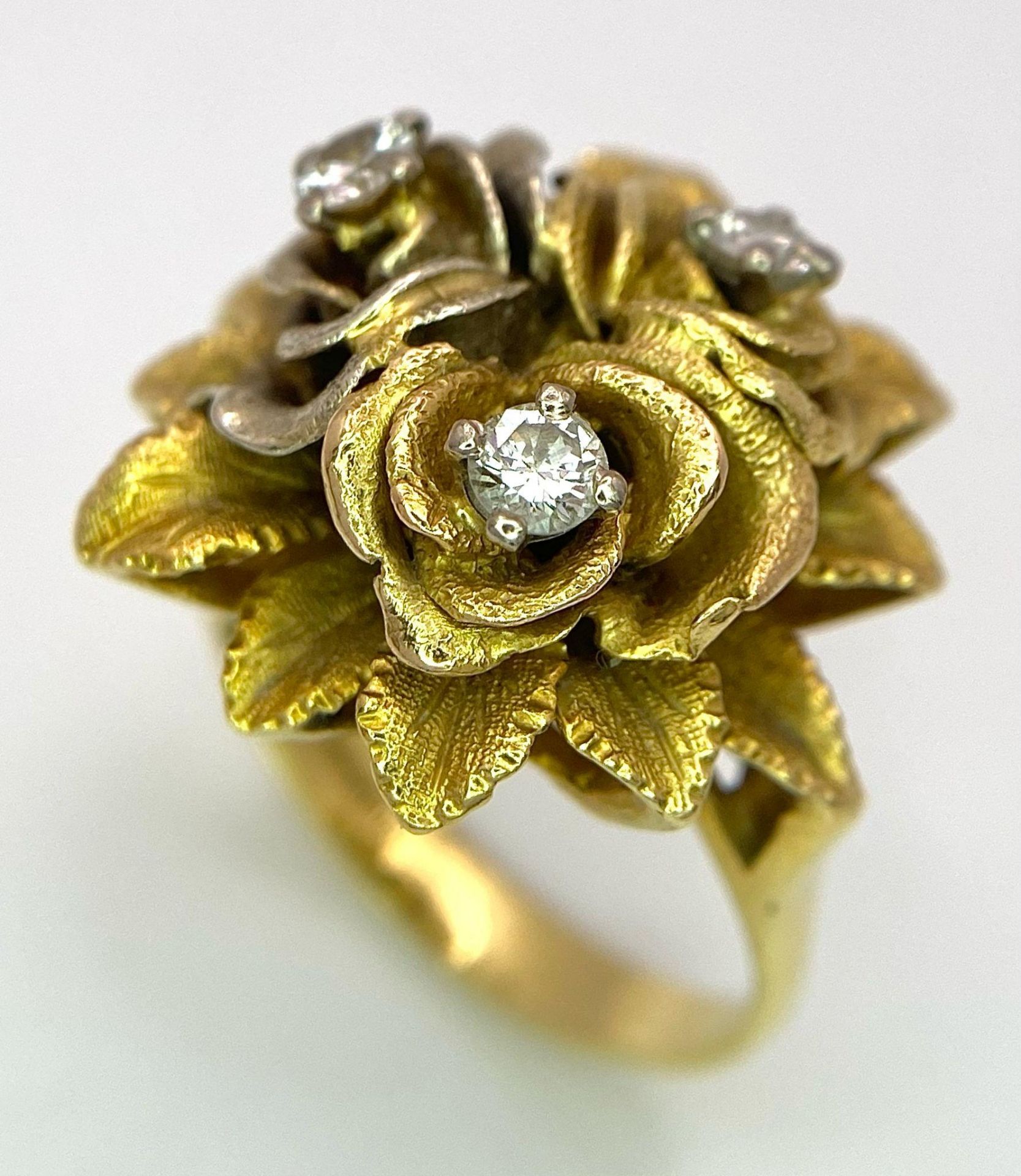 An 18K Yellow Gold and Diamond Floral Design Ring. A rich cluster of golden petals give sanctuary to