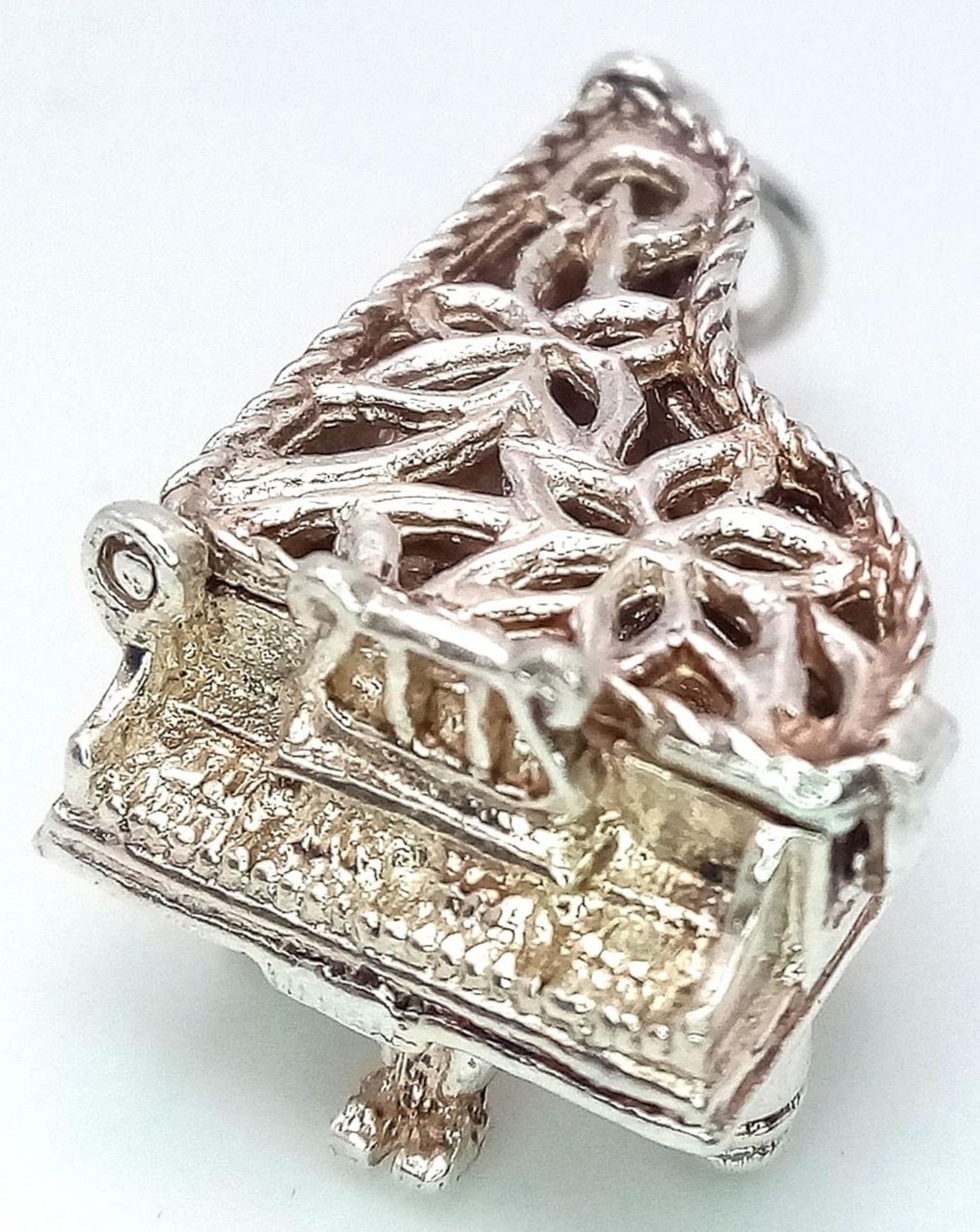 A Sterling Silver Piano Charm. Opens to reveal music notes. 2.5cm length, 4.5g weight. Ref: SC 7080