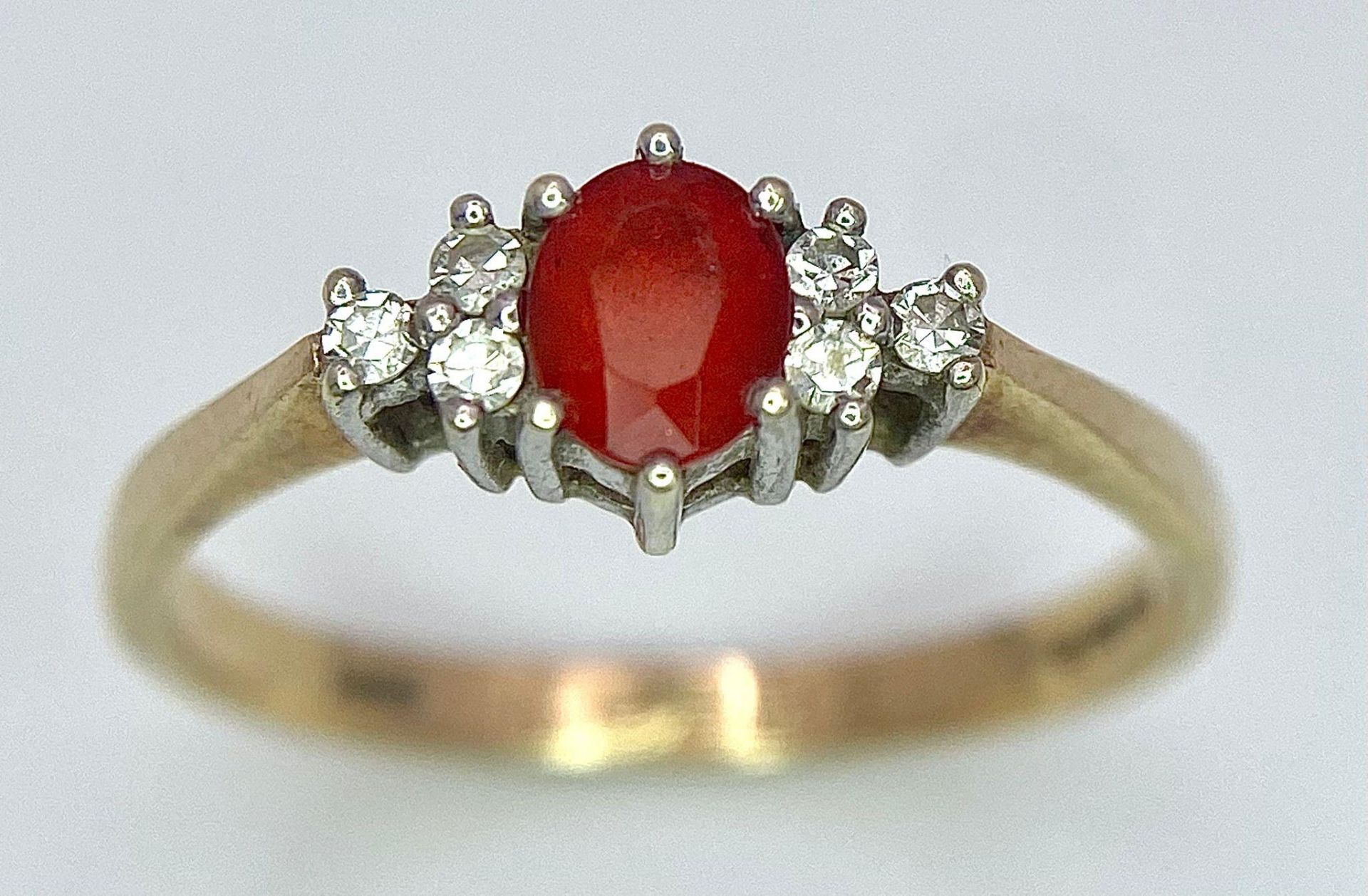 A Vintage 9K Yellow Gold, Red Sapphire and Diamond Ring. Oval sapphire with diamond accents. Size O.