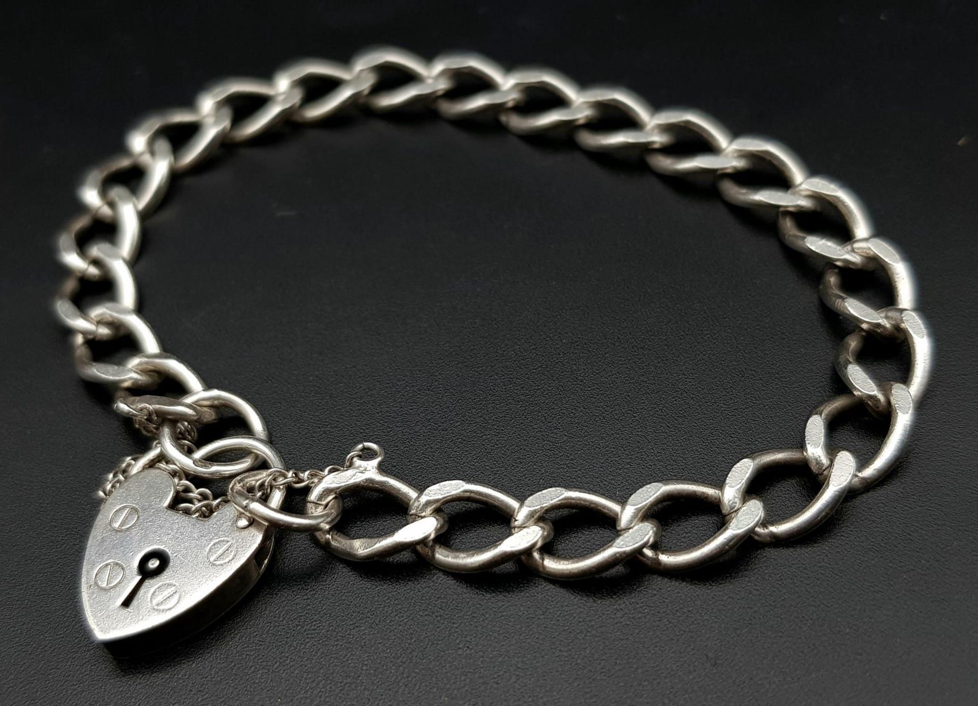 A vintage sterling silver curb bracelet with heart locket. Full London hallmarks, 1975. Total weight