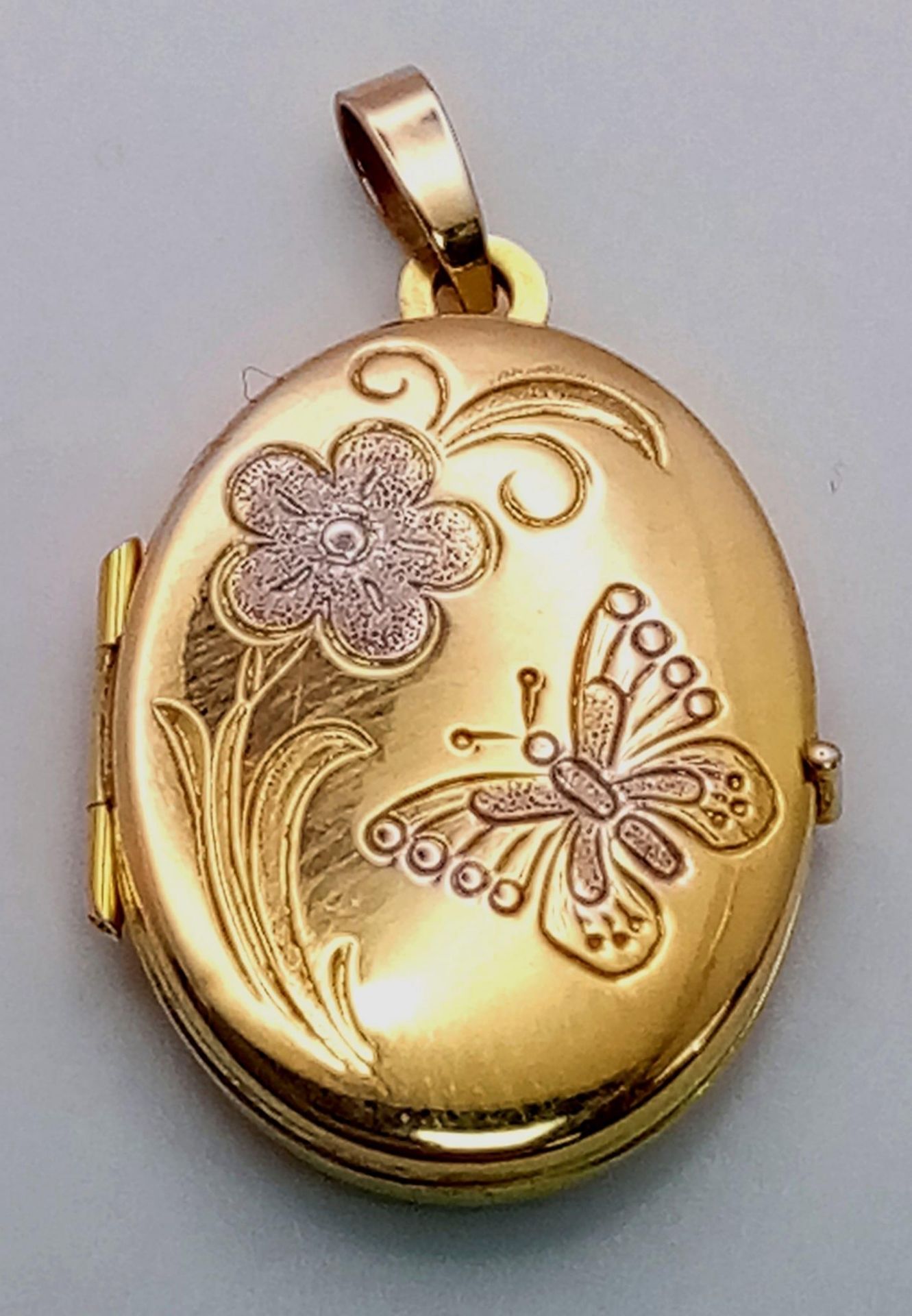 A 9K Yellow Gold Oval Locket Pendant. Decorative white gold floral scene. 3cm. 2.2g weight.