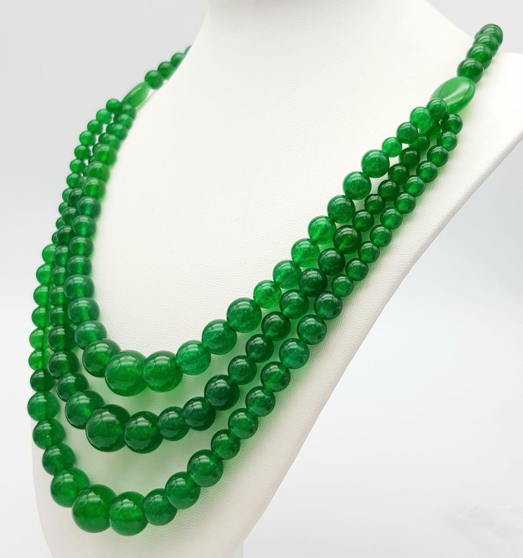 A Chinese Expansive Three Row Green Jade Necklace. A green jade bead necklace gives way to a three - Image 3 of 7