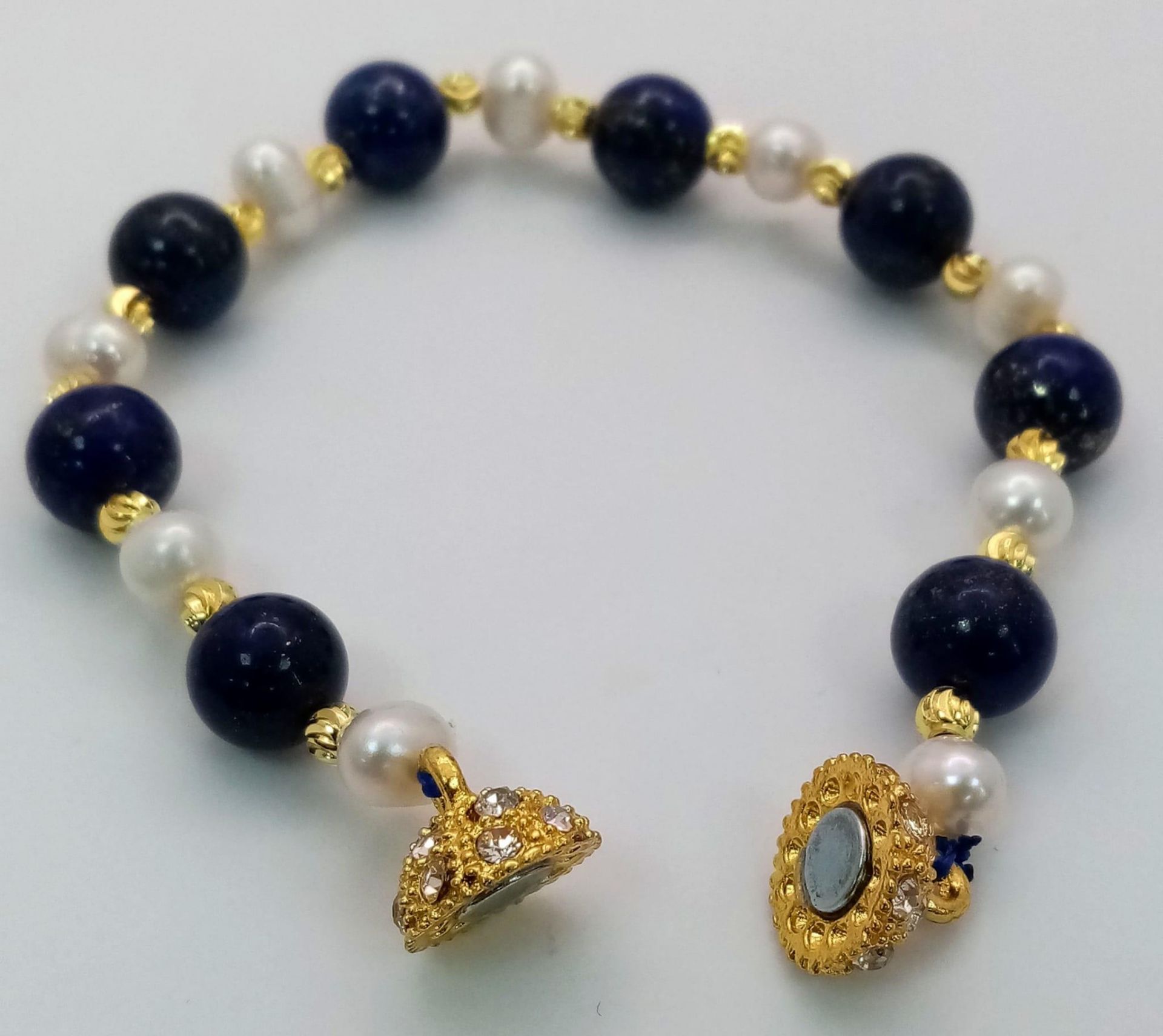 A Lapis Lazuli and Cultured Pearl Bracelet. Gilded spacers and magnetic glitterball clasp. - Image 2 of 4