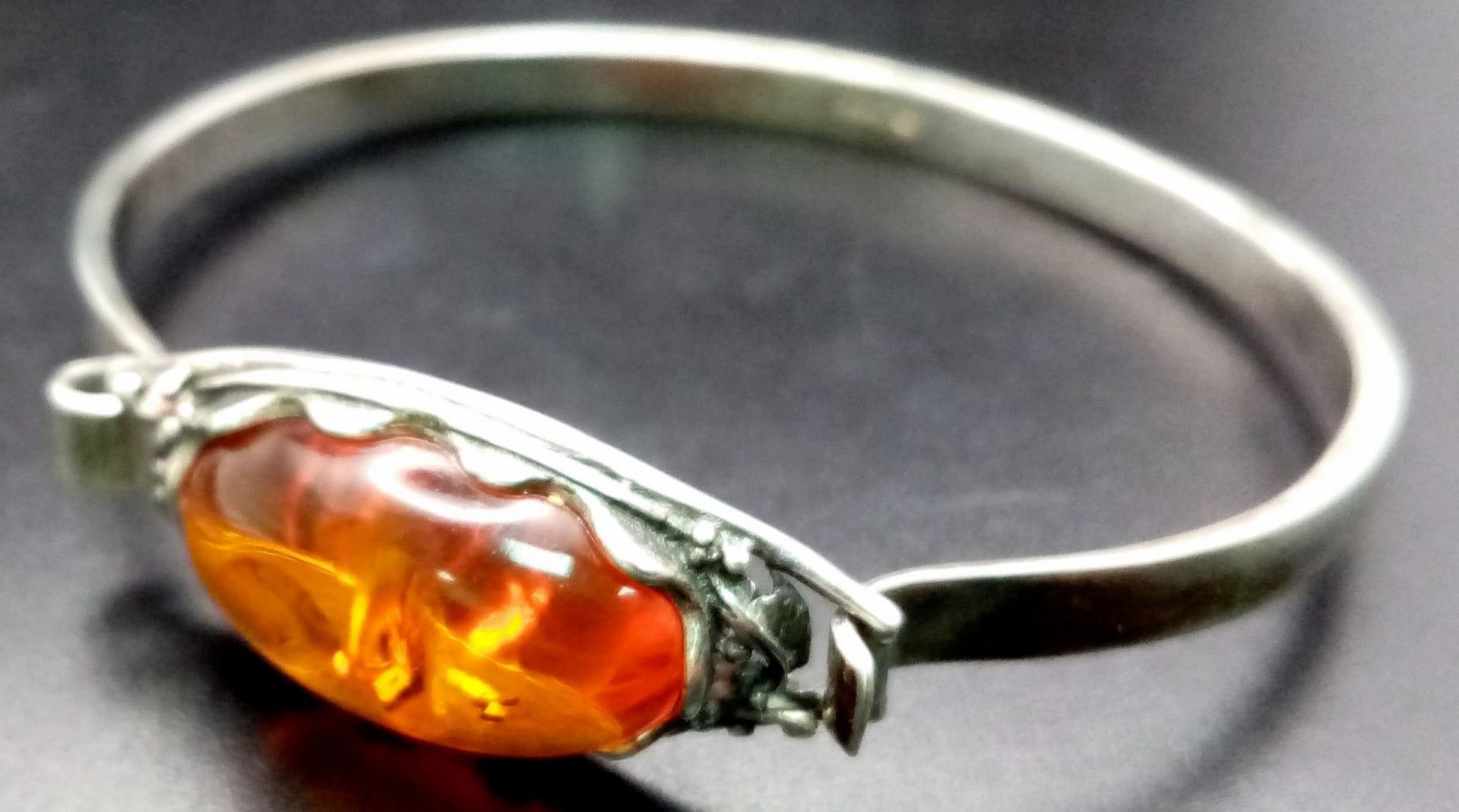 A vintage sterling silver Amber bangle. Total weight 15.7G. Widest inner length 6.7cm.