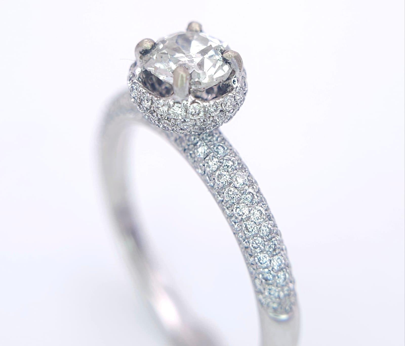A 14K WHITE GOLD DIAMOND DIAMOND HALO RING WITH FULL SET SHOULDERS AND COLLET. 1.10CT. 2.9G. SIZE - Image 3 of 7