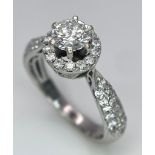 An 18K White Gold Diamond Ring. Central 0.75ct brilliant round cut diamond with a diamond halo and