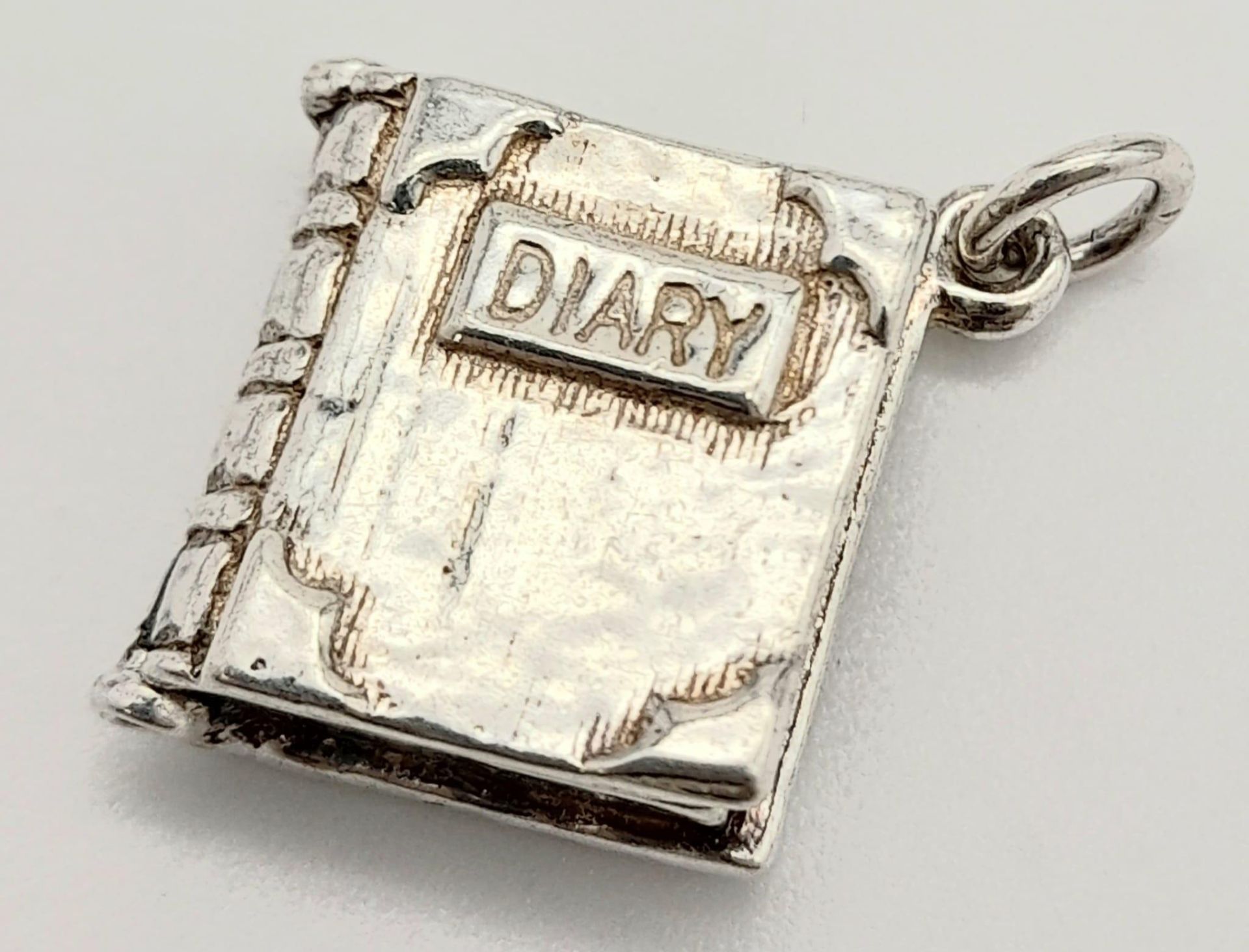 A STERLING SILVER DIARY CHARM/PENDANT, WHICH OPENS UP, WEIGHT 4.8G