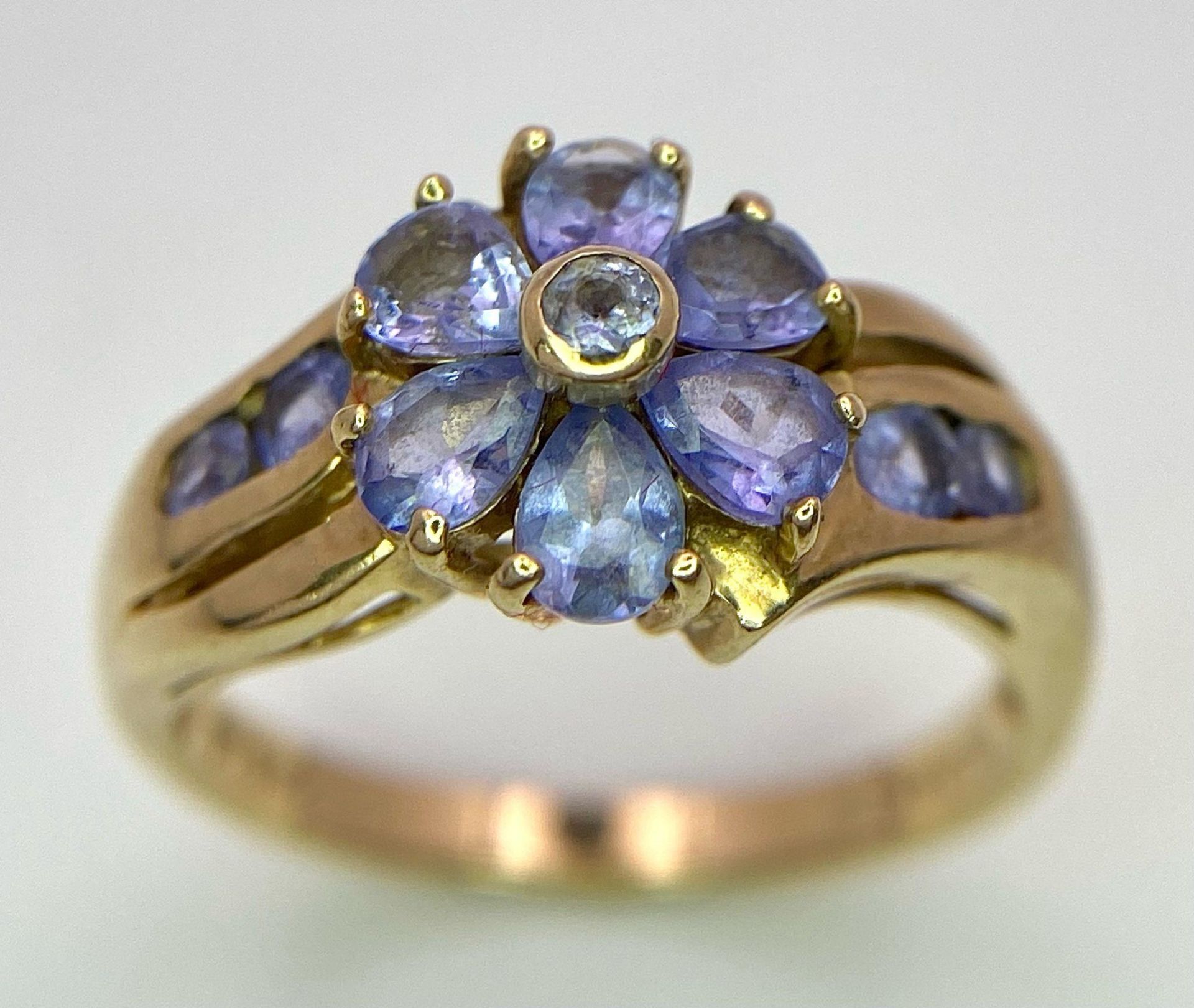 A 9K GOLD RING WITH FLORAL SHAPED AMETHYST STONES . 3.2gms size N