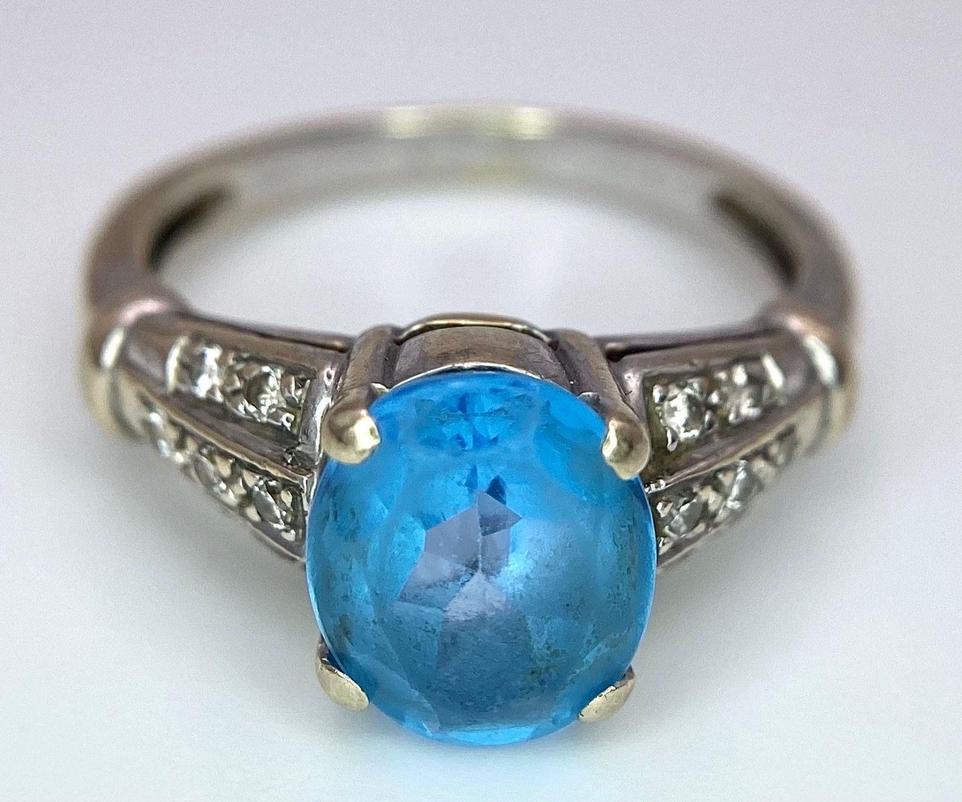 A vintage, 9 K white gold ring with a large, oval cut, vivid blue aquamarine and three bands of - Image 4 of 5
