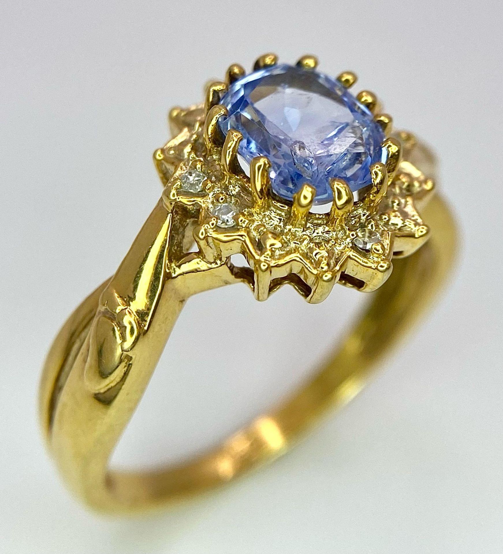 An 18K Yellow Gold Diamond and Sapphire Ring. Central oval sapphire with a diamond surround. Size O.