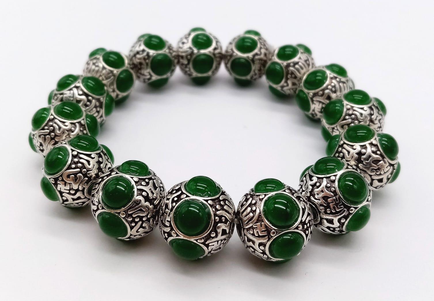 A Tibetan Silver and Green Jade Expandable Bracelet. Decorative jade cabochons and ancient Tibetan