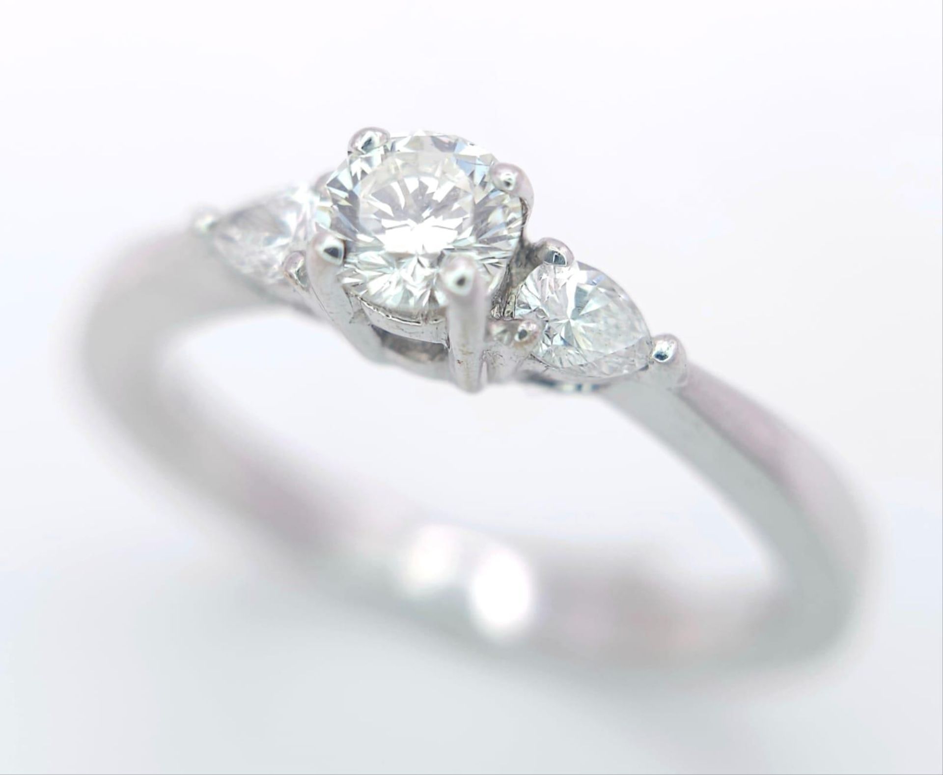 AN 18K WHITE GOLD DIAMOND RING WITH PEAR SHAPED DIAMOND ACCENTS ON SHOULDERS. 0.40CTW OF PEAR SHAPED