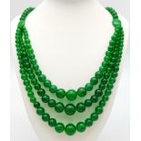 A Chinese Expansive Three Row Green Jade Necklace. A green jade bead necklace gives way to a three