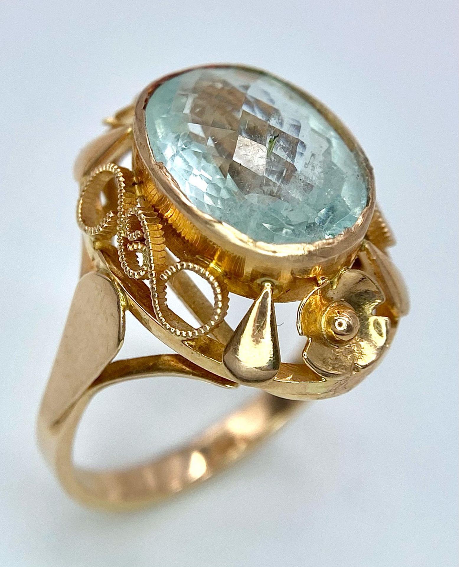 An 18K Rose Gold Aquamarine Ring. 6ct central aquamarine gemstone on a raised scroll foundation.