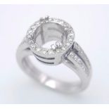 AN 18K WHITE GOLD DIAMOND RING - SET HALO MOUNT WITH DIAMOND SET SPLIT SHOULDERS. SHANK RING MOUNT