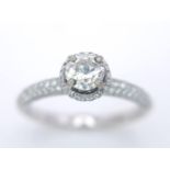 A 14K WHITE GOLD DIAMOND DIAMOND HALO RING WITH FULL SET SHOULDERS AND COLLET. 1.10CT. 2.9G. SIZE