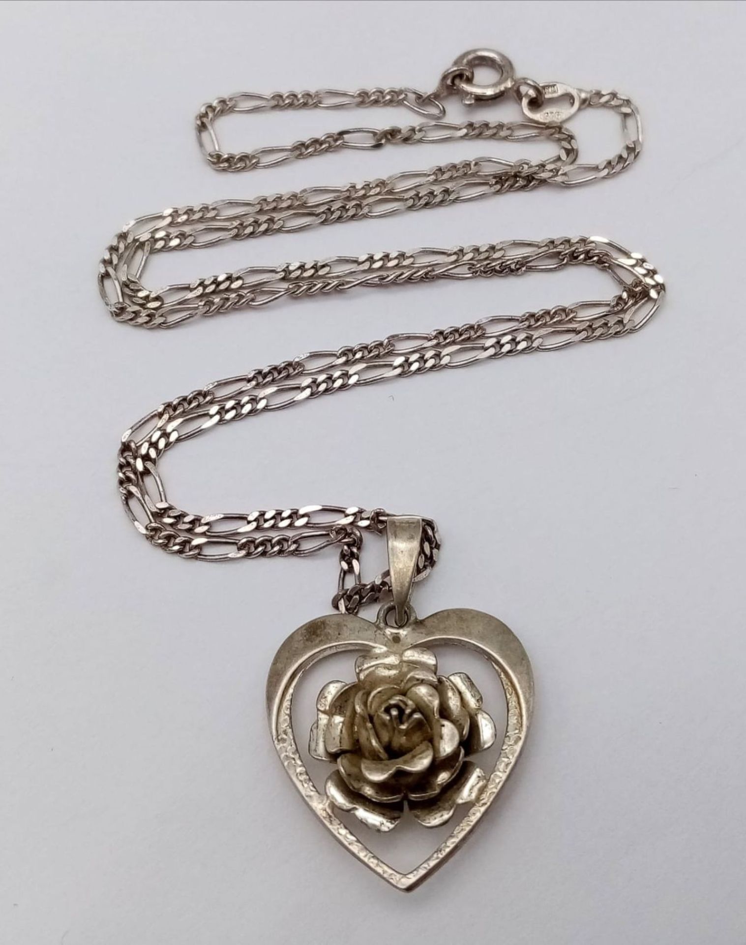 A vintage sterling silver floral heart pendant on 925 silver figaro chain. Total weight 6.5G.