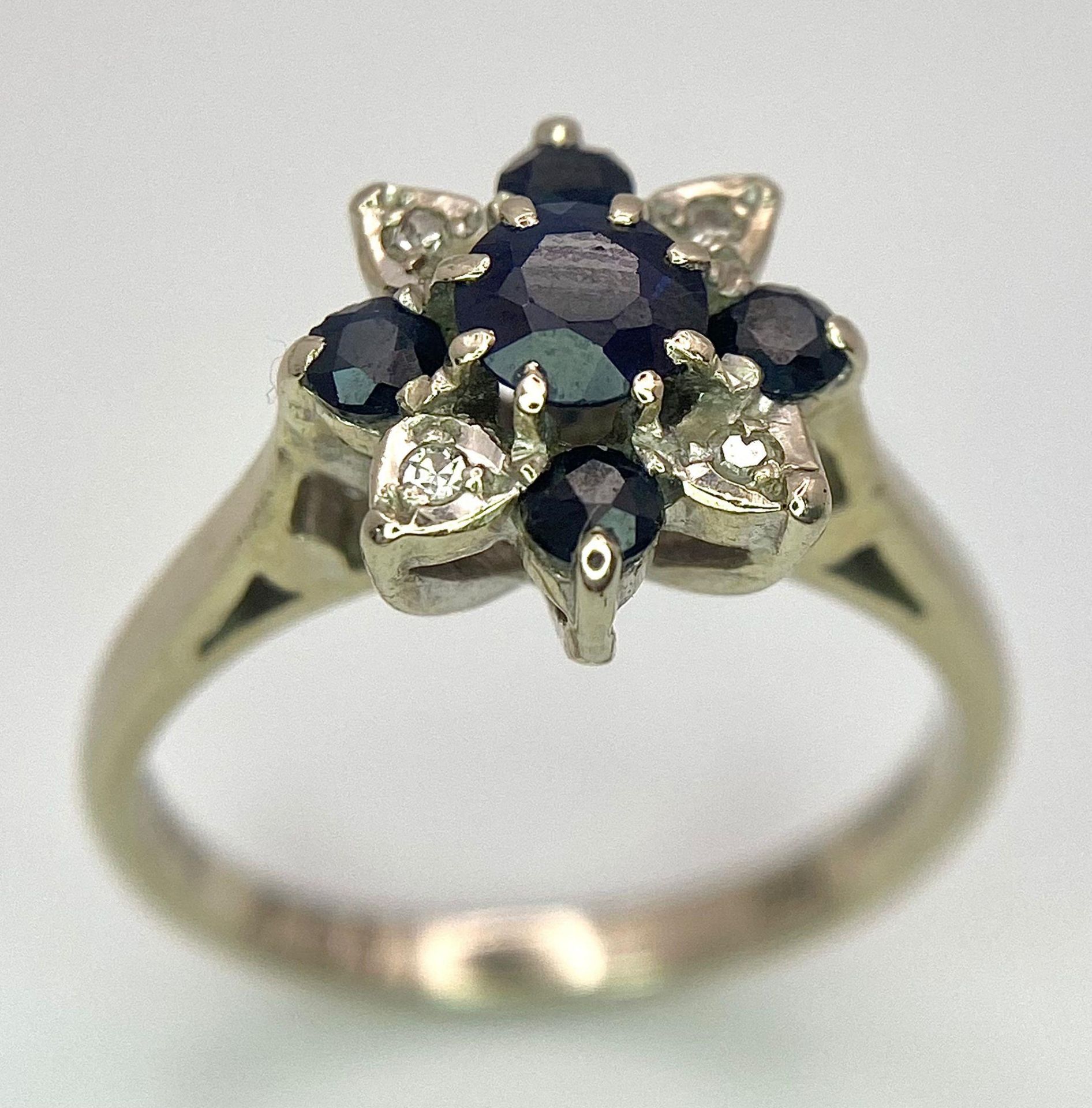 An 18 K white gold ring with a cluster of diamonds and dark blue sapphires. Size: M, weight: 4 g.