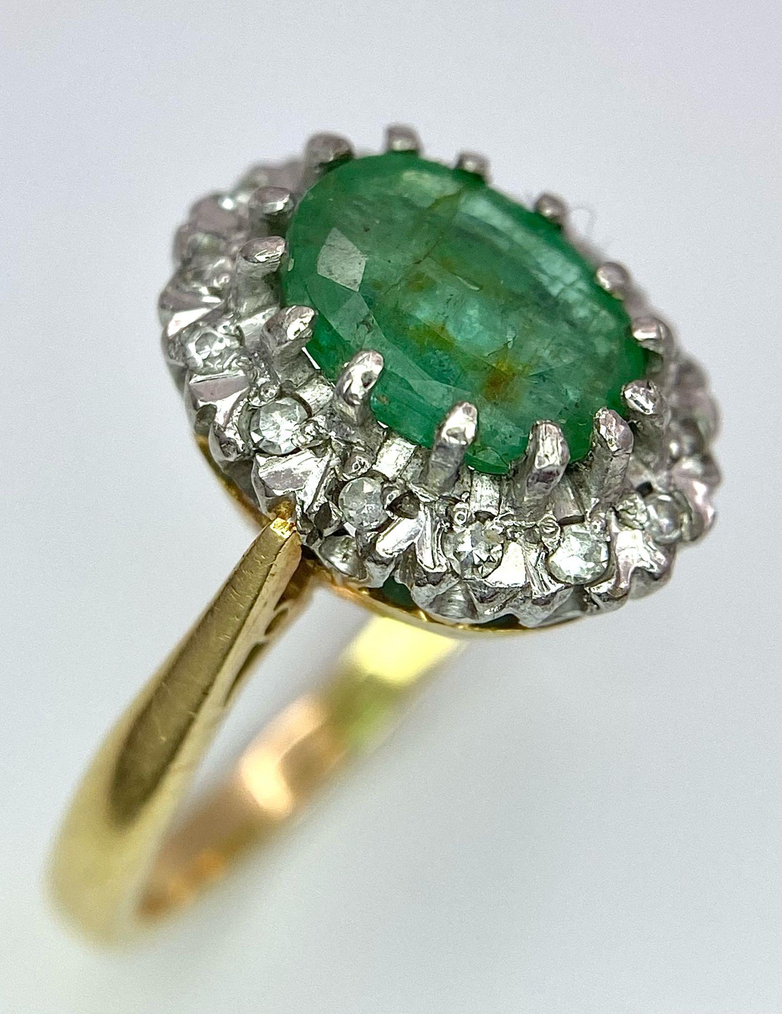 An 18K Yellow Gold, Emerald and Diamond Ring. Central 2ct emerald with a diamond surround. Size J.