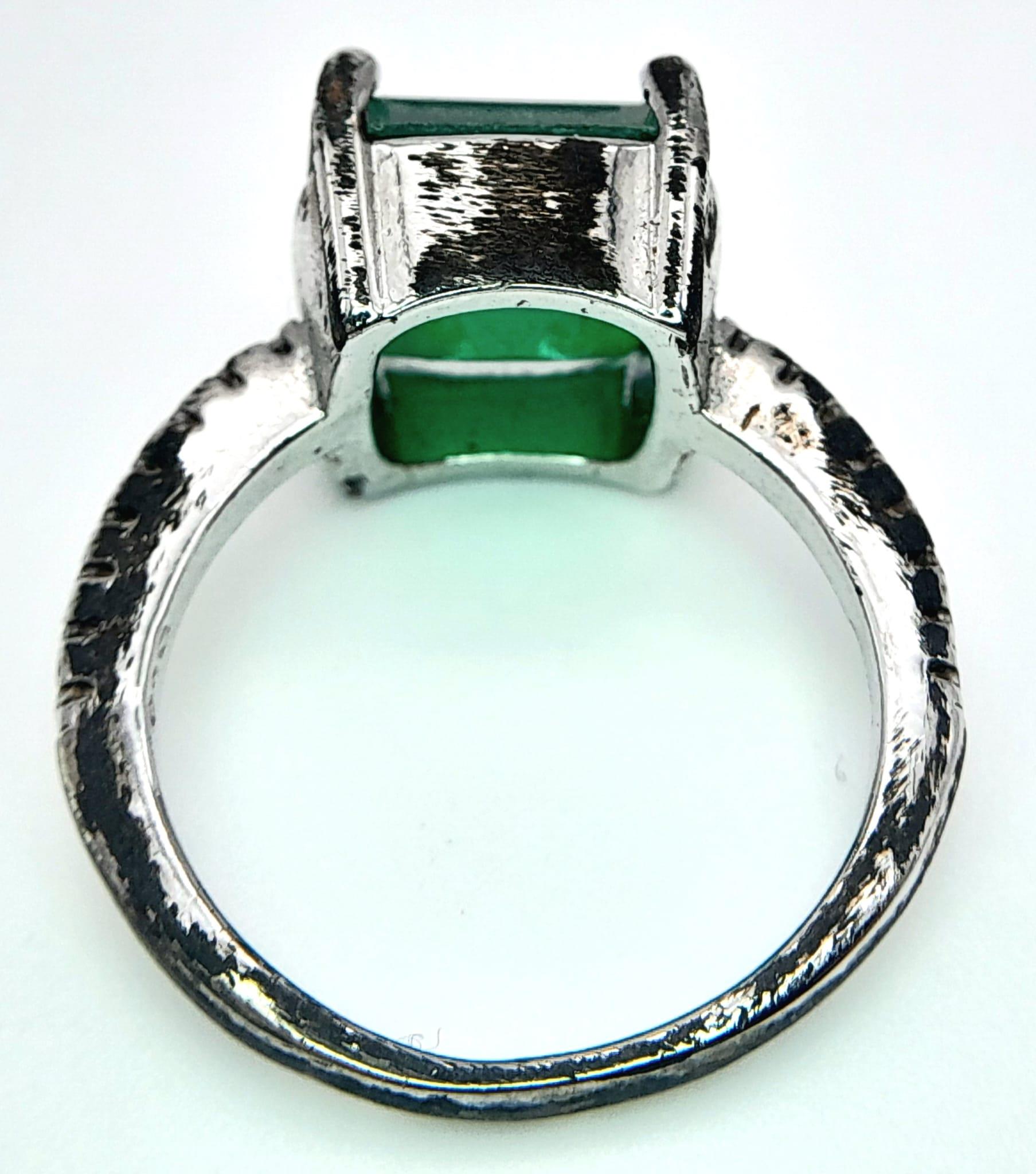 A sterling silver ring with an emerald cut synthetic emerald and cubic zirconia on the shoulders. - Image 7 of 8