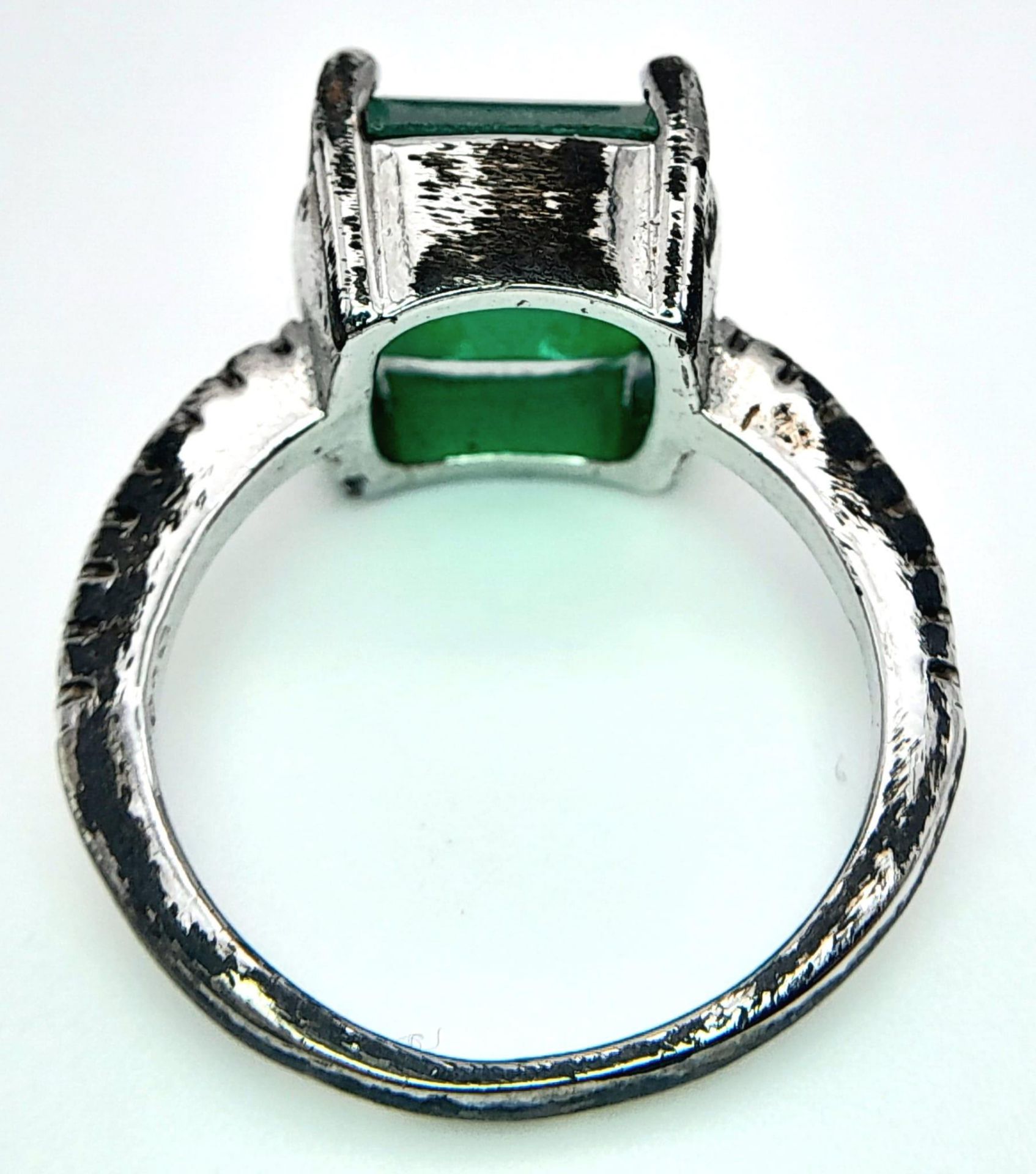 A sterling silver ring with an emerald cut synthetic emerald and cubic zirconia on the shoulders. - Image 7 of 8