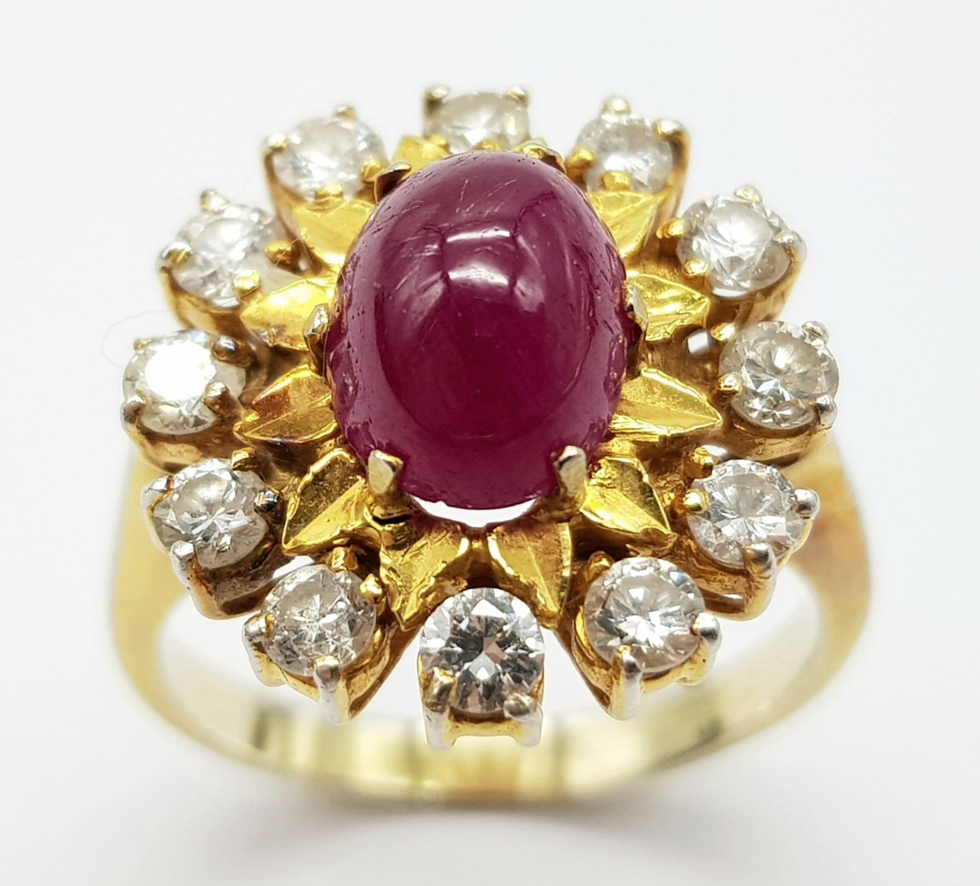 An 18K Gold (tested) Ruby and Diamond Ring. A 1.5ct high-grade ruby cabochon with a brilliant cut 12