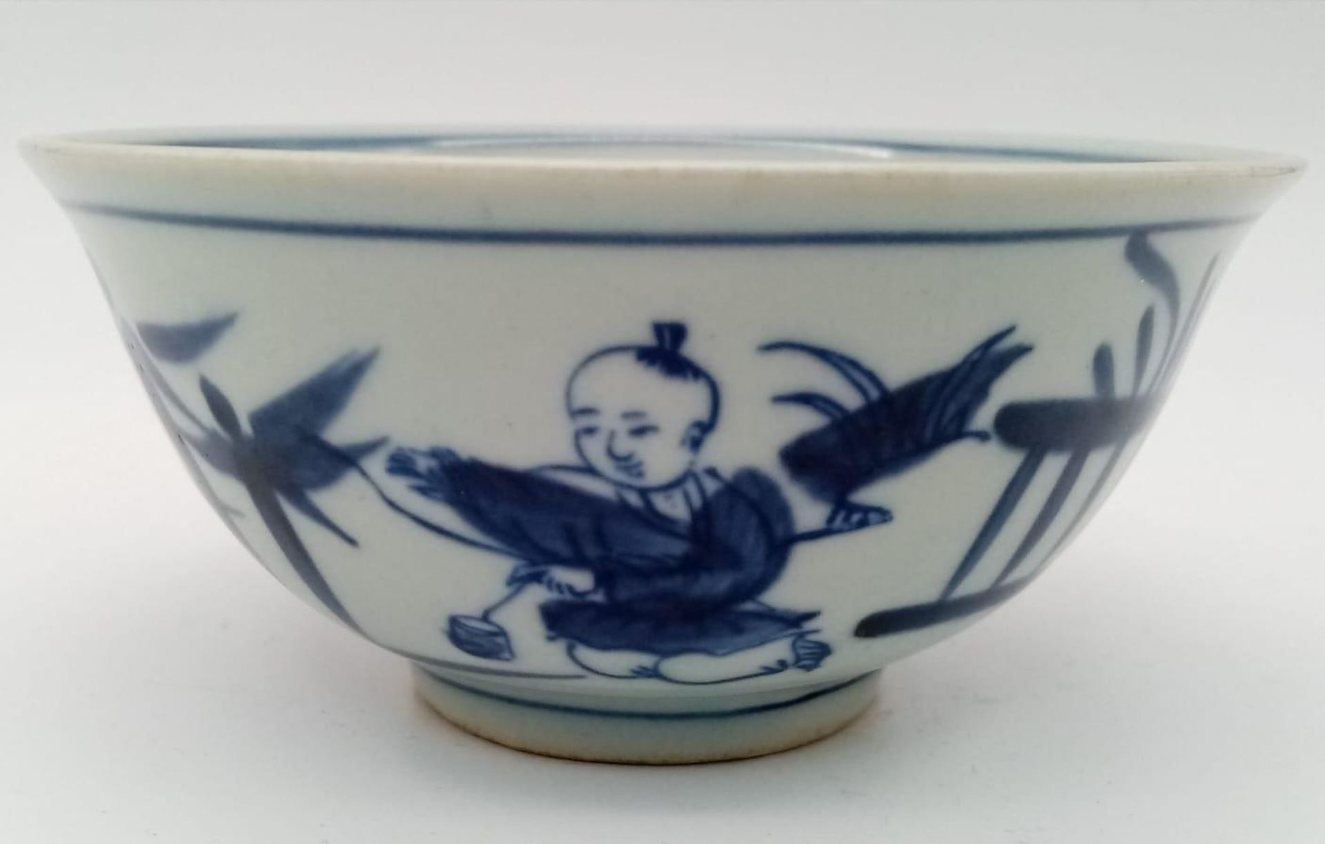 A Chinese blue and white hand painted bowl decorated with children playing with birds. White