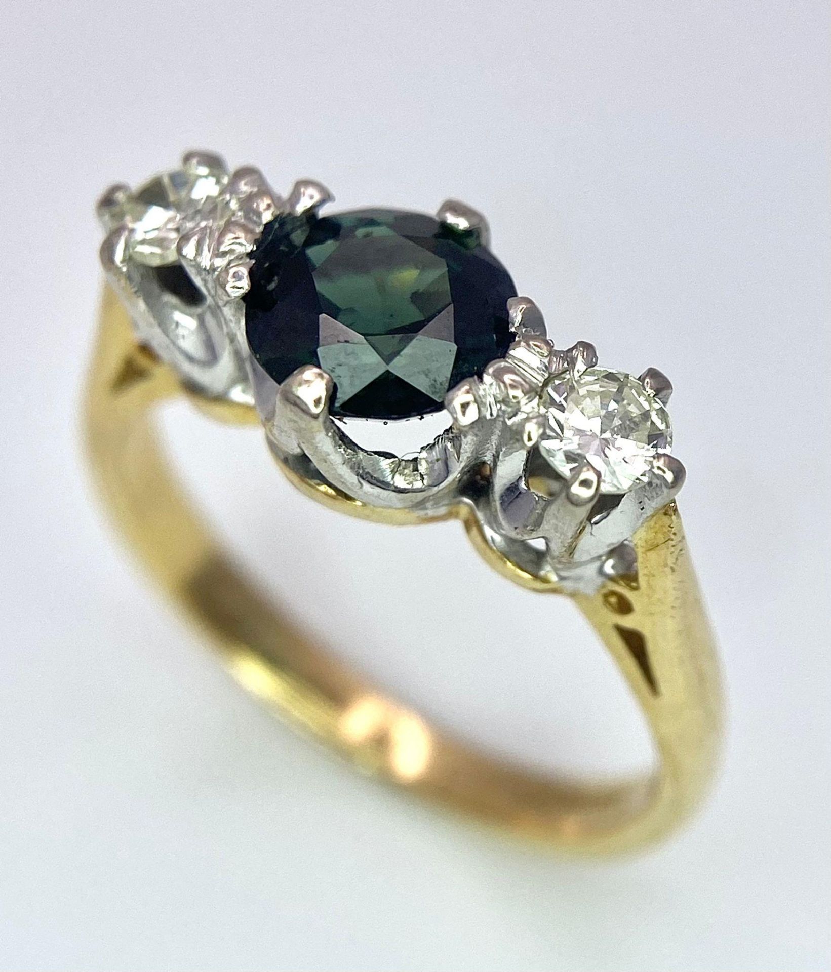 An 18K White Gold, Diamond and Sapphire Ring. Central round cut sapphire with a diamond either side.