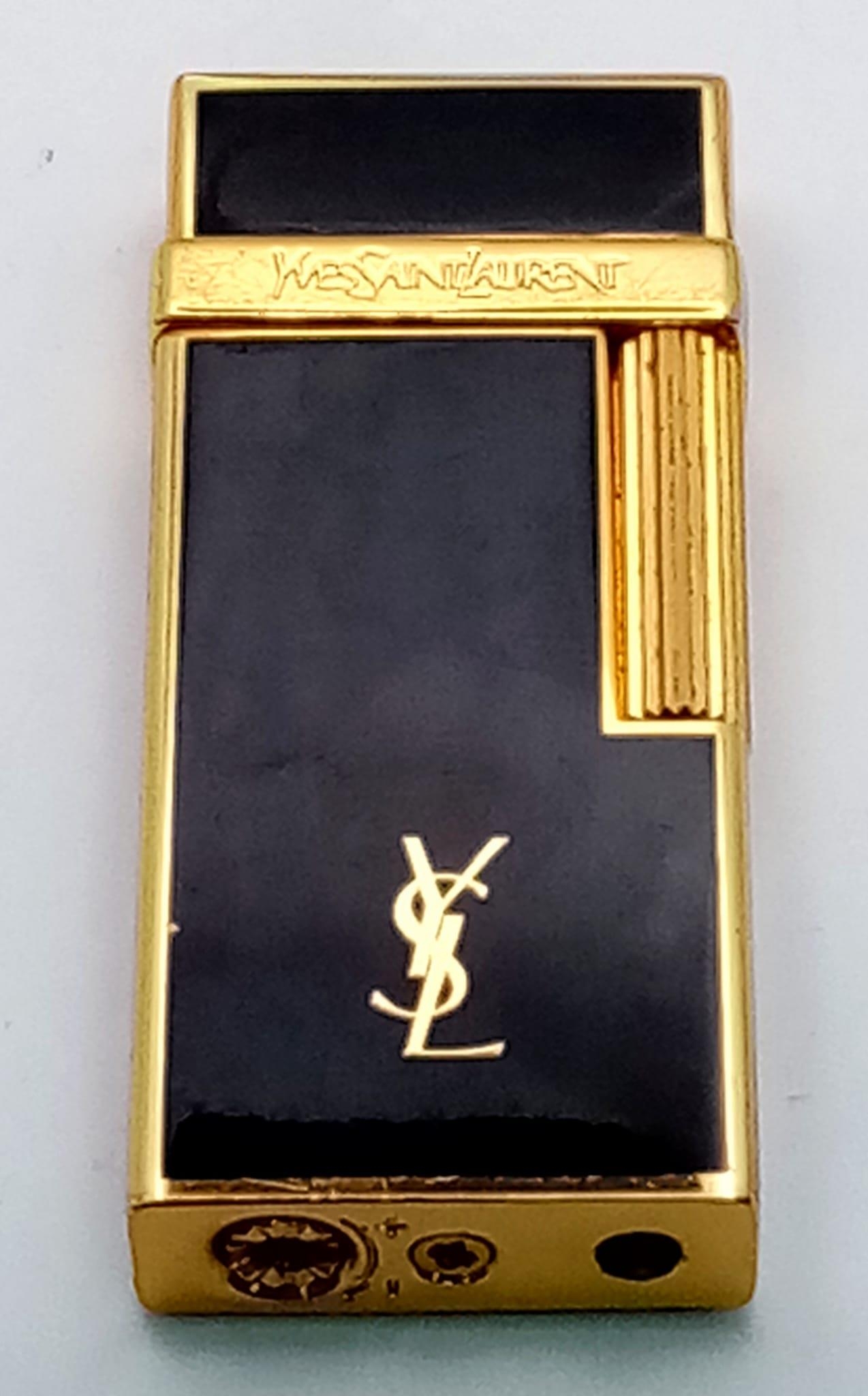 A very elegant Yves Saint Laurent gold plated and black enamelled lighter, dimensions: 63 x 26 x