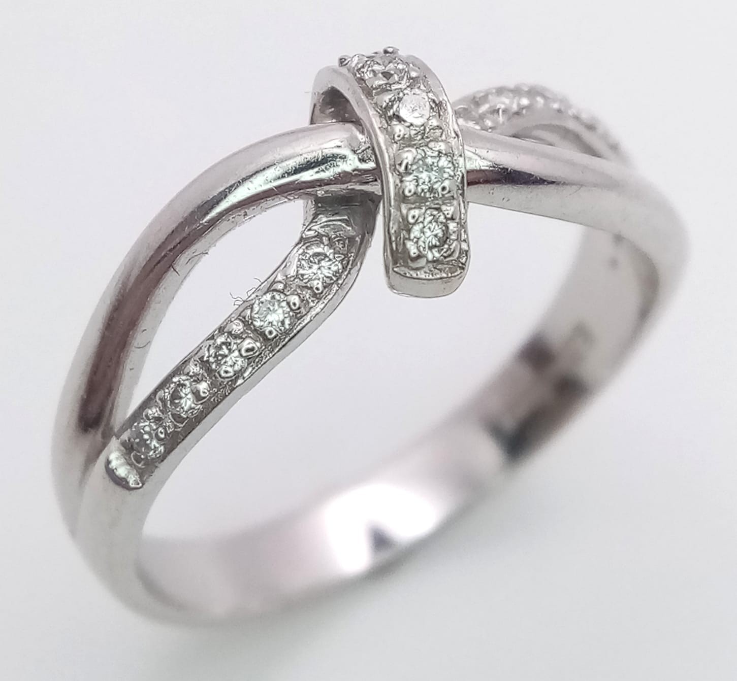 A FANCY 18K WHITE GOLD DIAMOND KNOTTED RING, APPROX 0.15CT DIAMONDS, WEIGHT 3.8G SIZE N