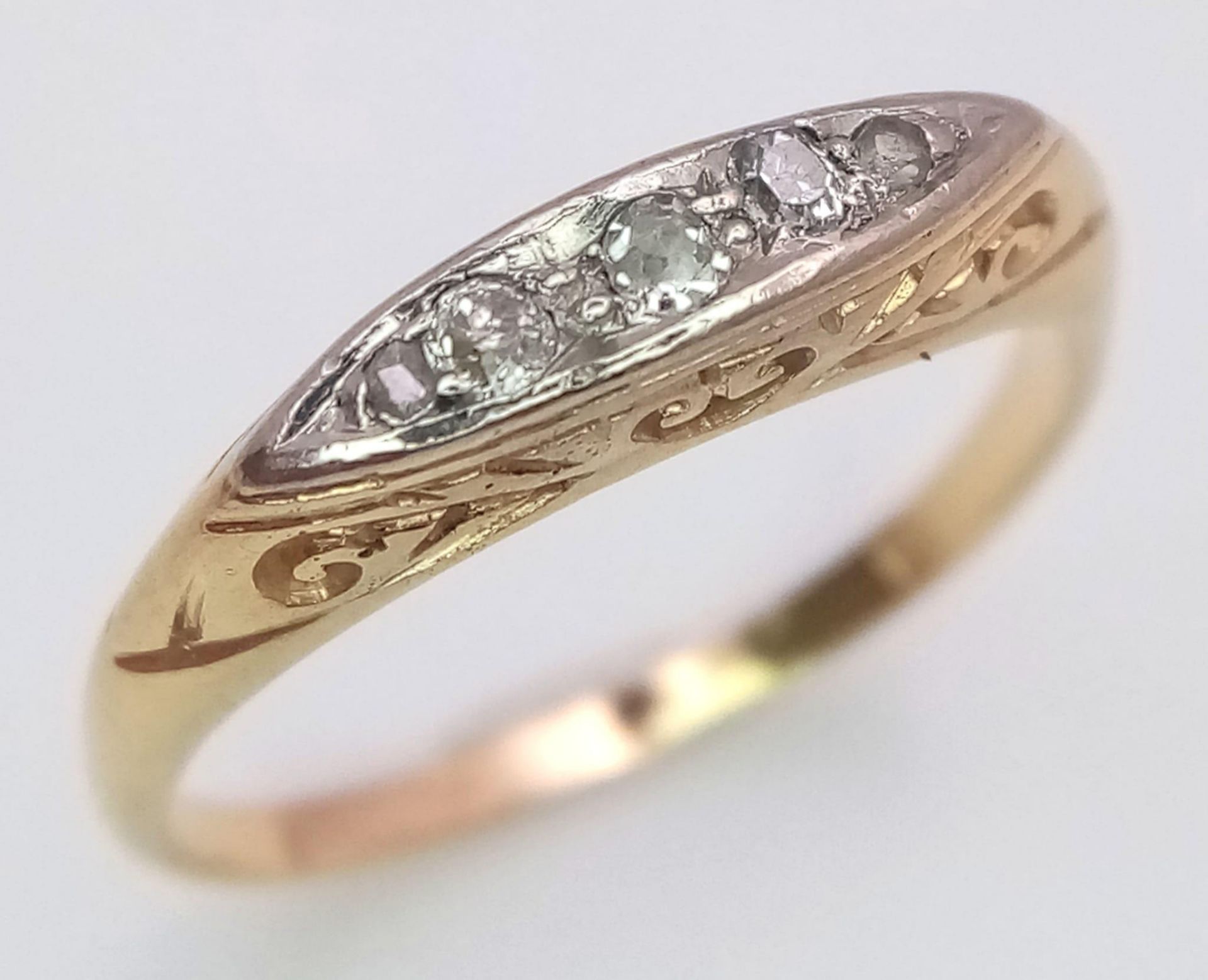 An antique yellow gold (tests 18 K) ring with a band of five old cut diamonds resting on a hand-