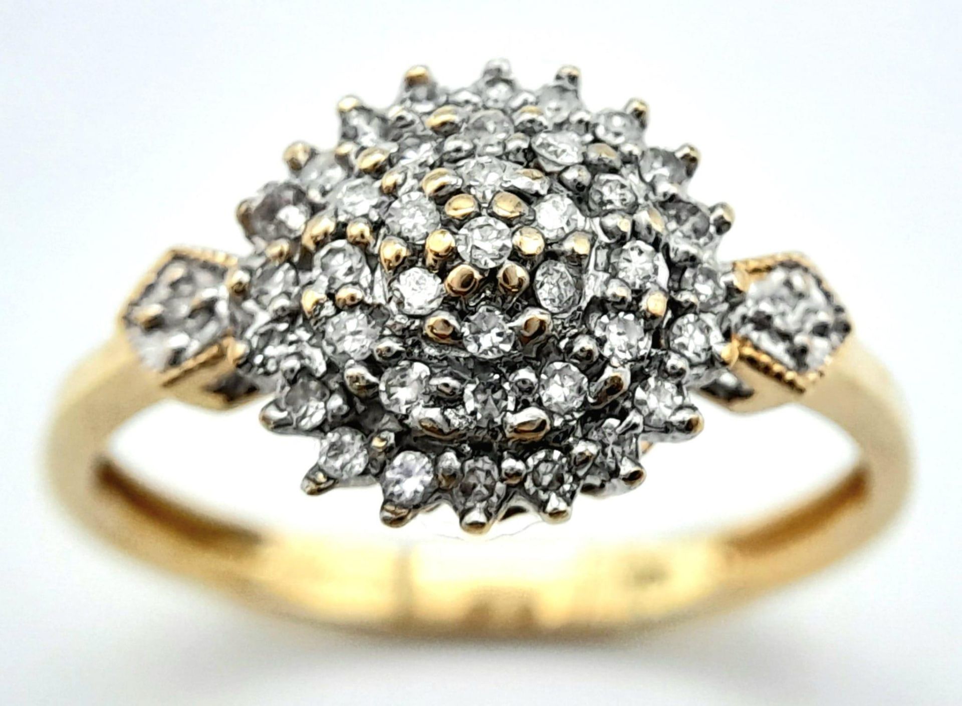 A 9K YELLOW GOLD DIAMOND SET CLUSTER RING. 0.25CTW. 2.2G. SIZE Q.