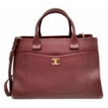 A Chanel Neo Executive Leather Tote Bag. Burgundy leather exterior with gold tone hardware and two