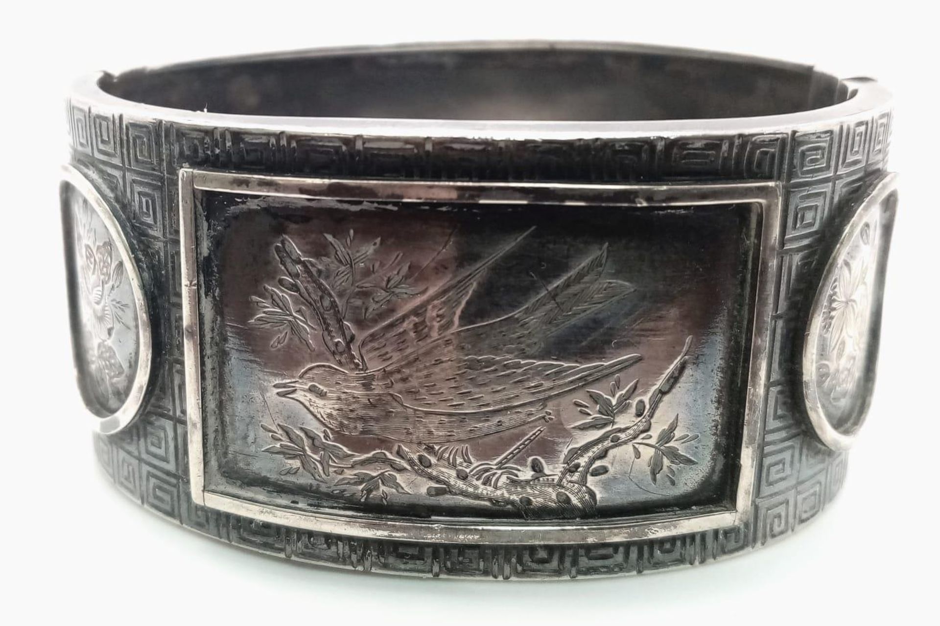 A vintage sterling silver click-on bangle (A/F) with oriental nature motif engravings. Total