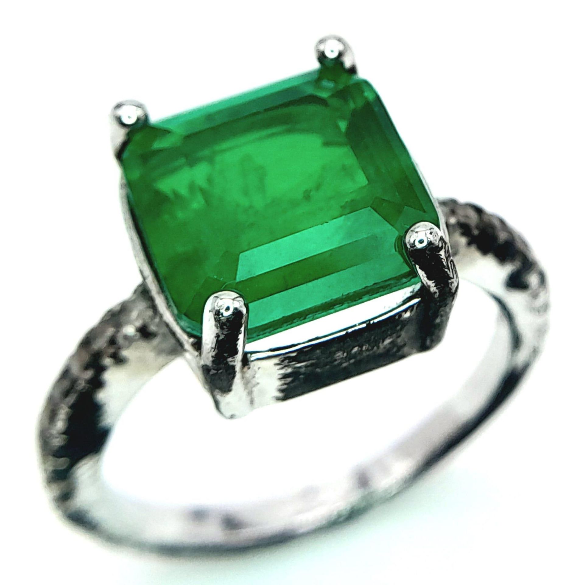 A sterling silver ring with an emerald cut synthetic emerald and cubic zirconia on the shoulders. - Image 3 of 8