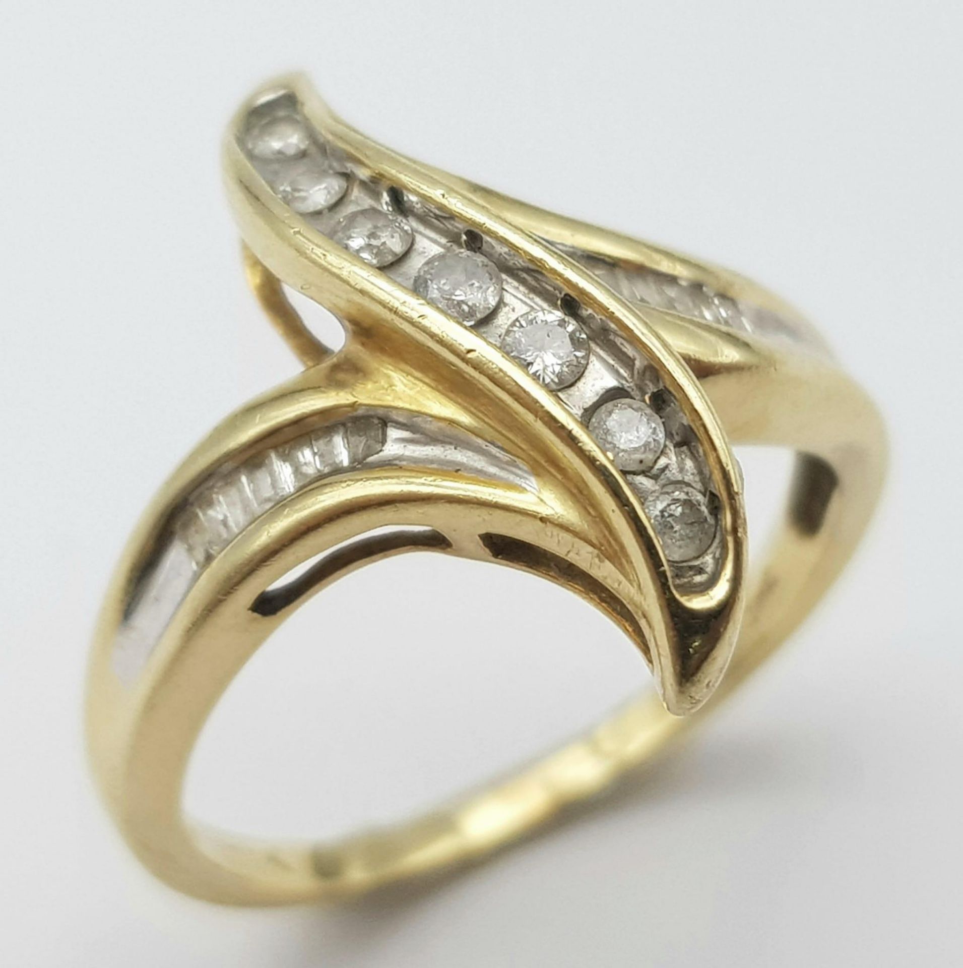 A 14K YELLOW GOLD DIAMOND SET FANCY TWIST RING. 0.20CT. 3.6G. SIZE O.