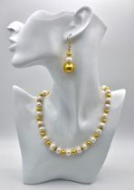 A classy, fresh water cultured white pearl necklace and earrings set, with gold plated parts and