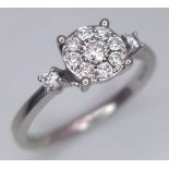 A 9 K white gold ring with a diamond cluster and a single diamond at the top of each shoulder, size: