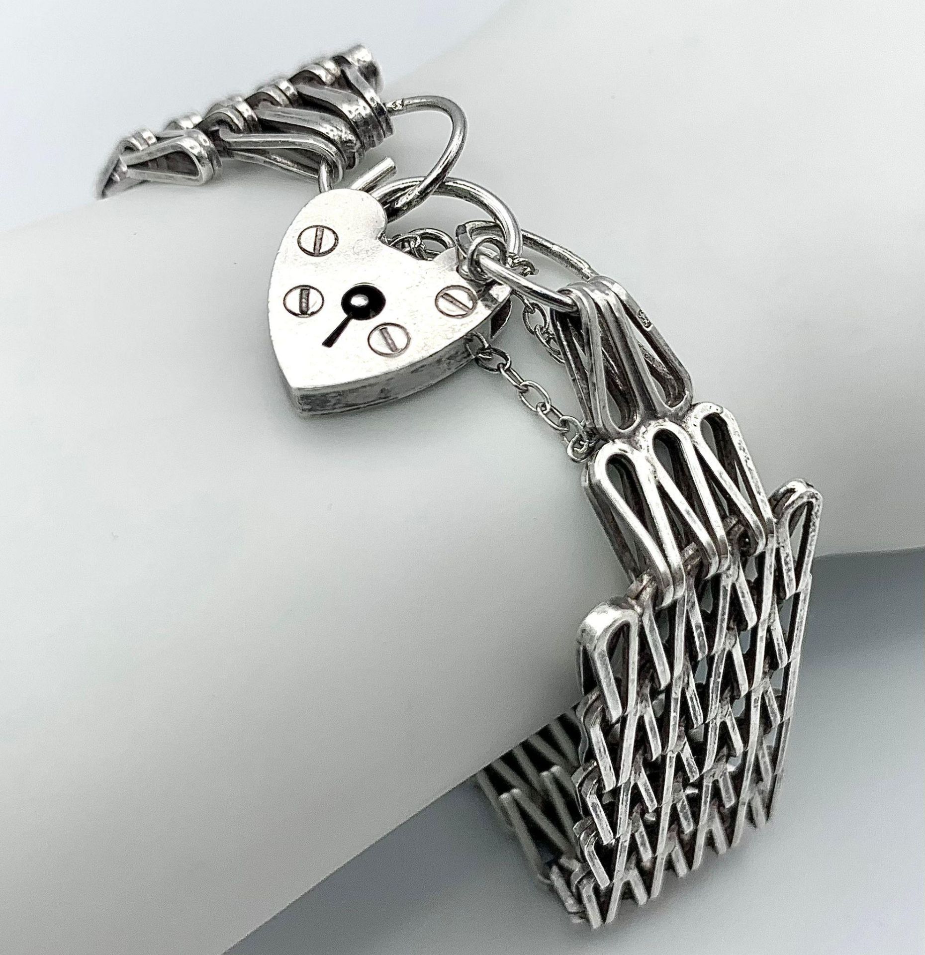 A vintage sterling silver bar gate link bracelet with hear locket. Full hallmarks London, 1976.