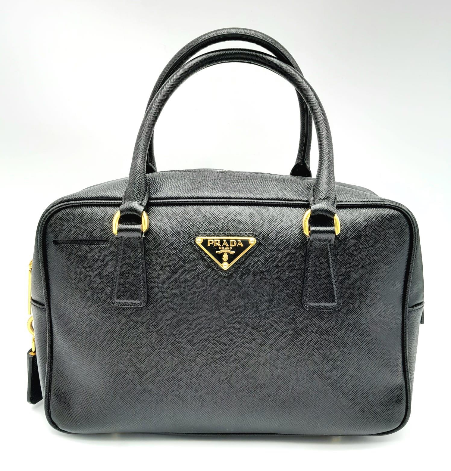 A Prada Black Bauletto Handbag. Saffiano leather exterior with gold-toned hardware, padlock, 2